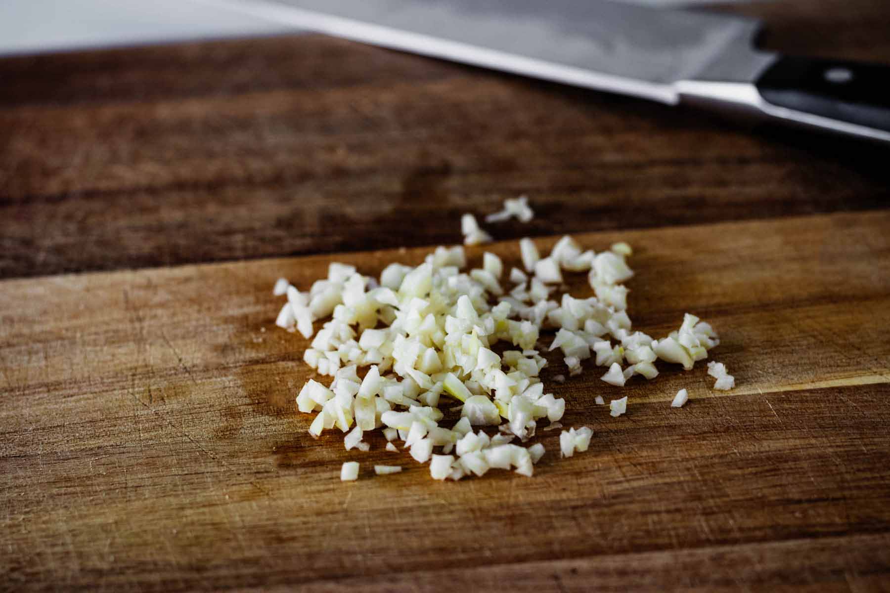 Close up of minced garlic on a cutting board.