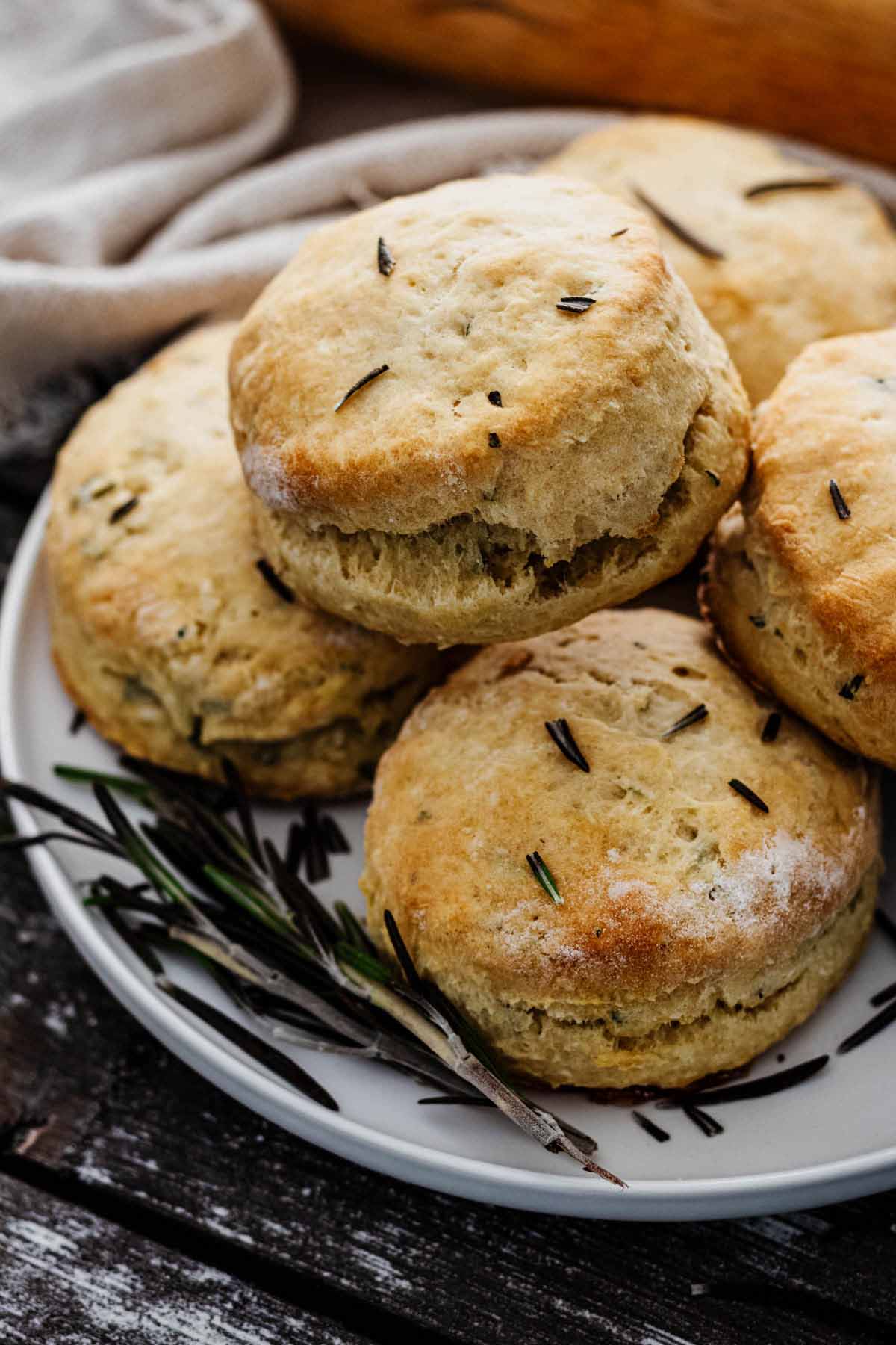 Close up of a stack of rosemary biscuits on a white plate.