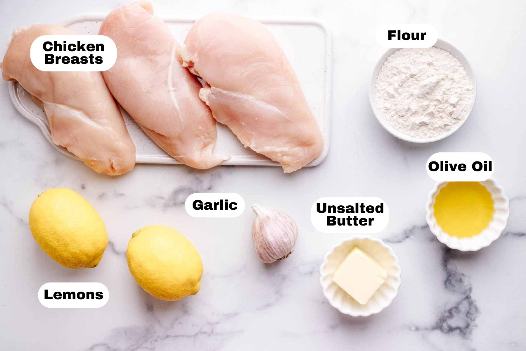 Chicken Limone ingredients including three large chicken breasts, flour, olive oil, unsalted butter, head of garlic, and two lemons