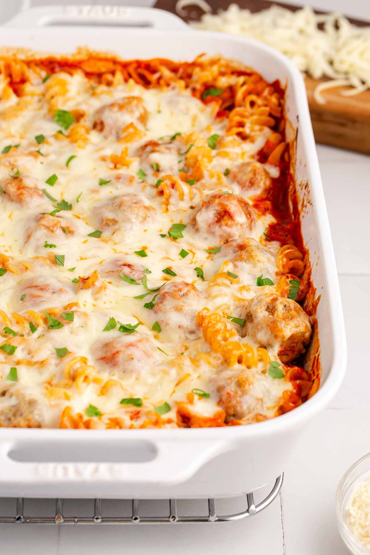Semi-close up of baked meatball casserole in a large white baking dish.