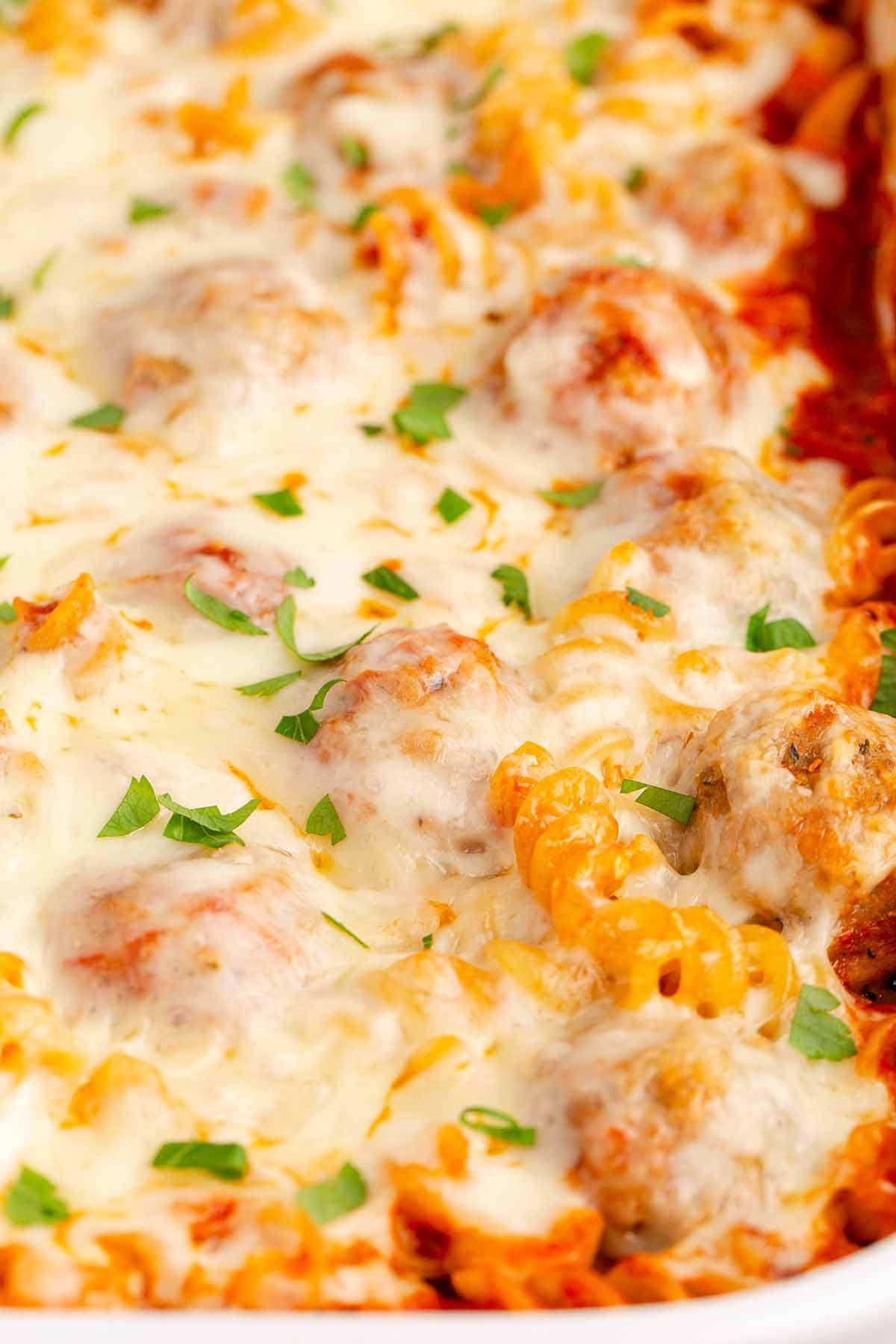 Close up of baked meatball casserole in a white casserole dish.