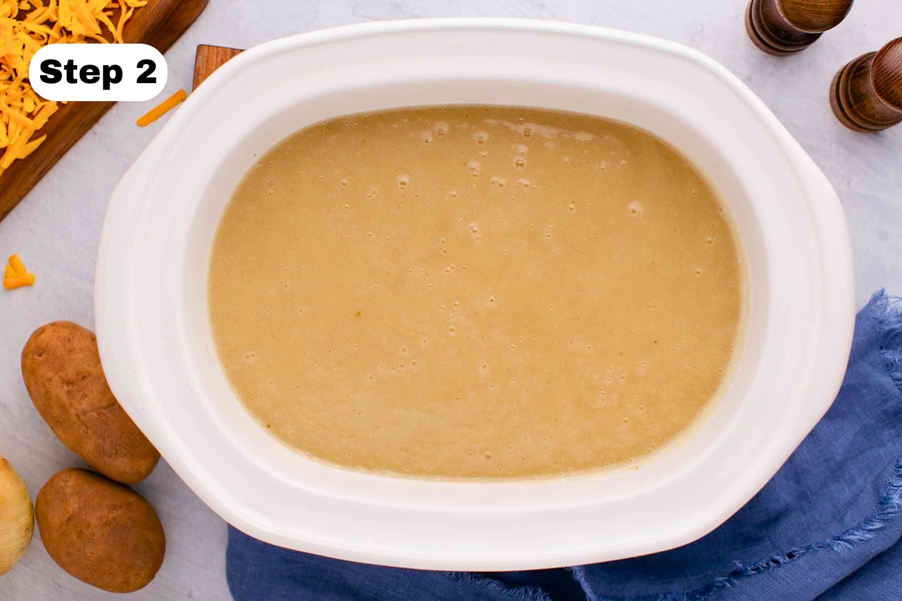 Blended cooked potato and onion mixture in a white slow cooker.