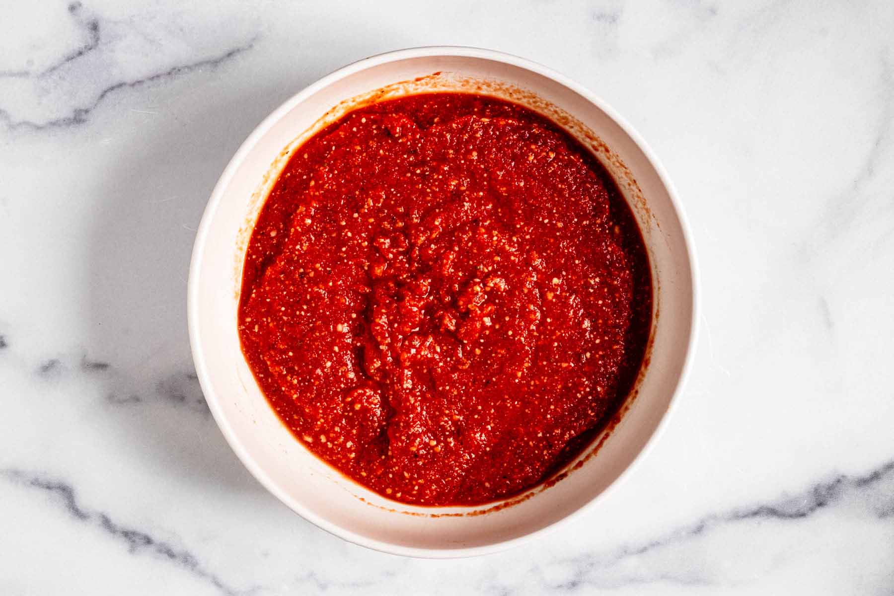 All pizza sauce ingredients combined in a white bowl
