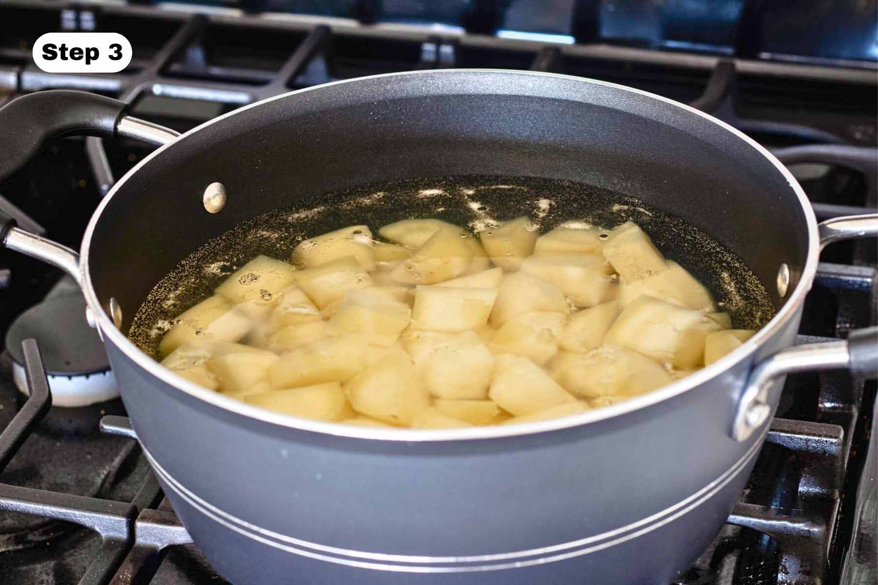 A pot of potatoes and water on a gas stove.
