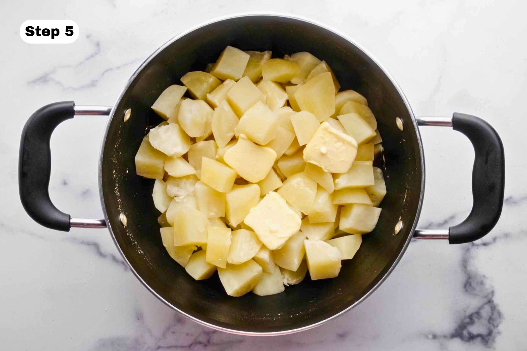 Butter melting over cooked potatoes in a large pot.