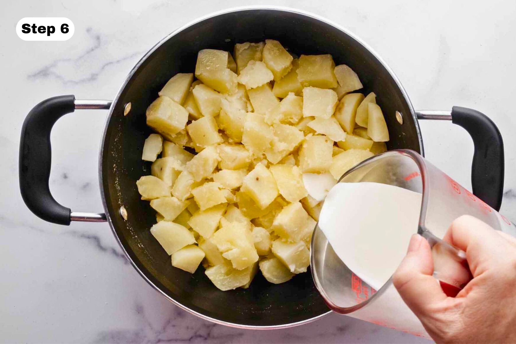 Heavy cream being poured over cooked potatoes.