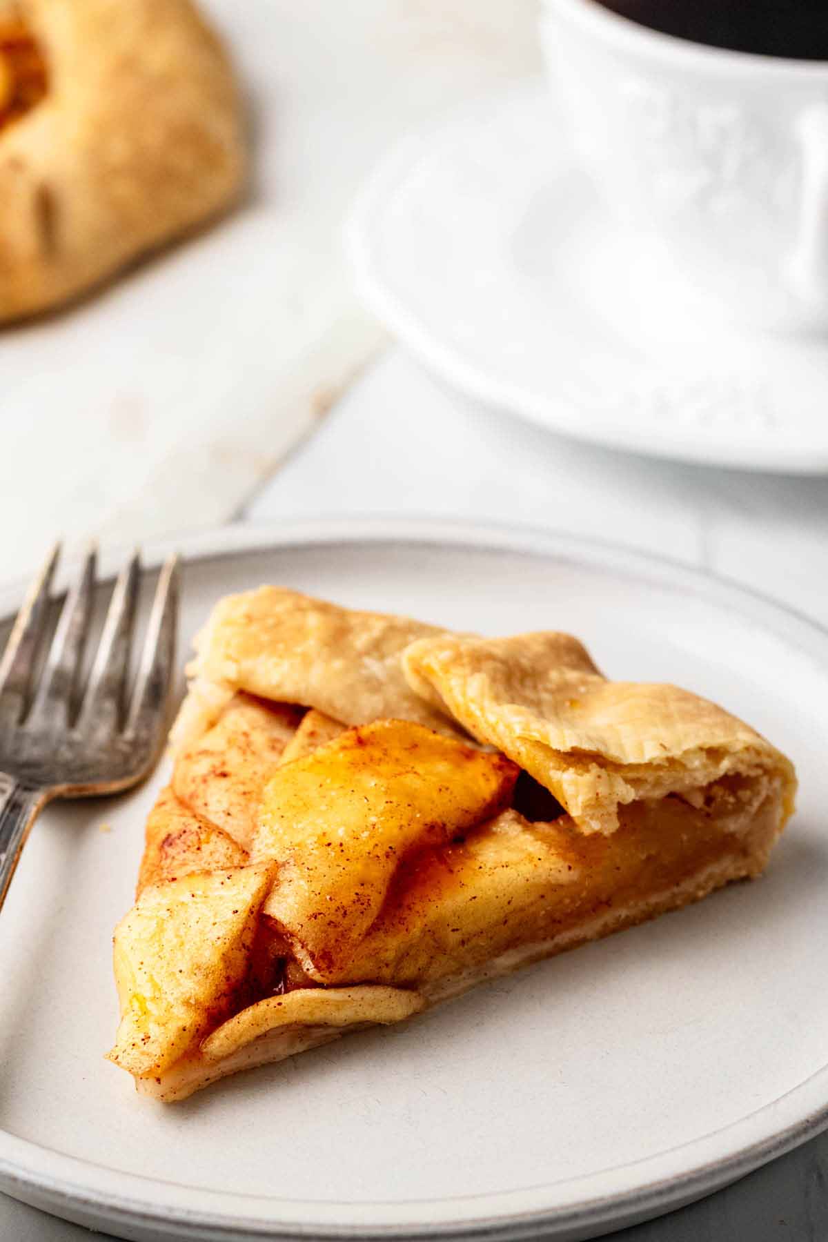 A slice of apple galette on a light grey plate with a fork.