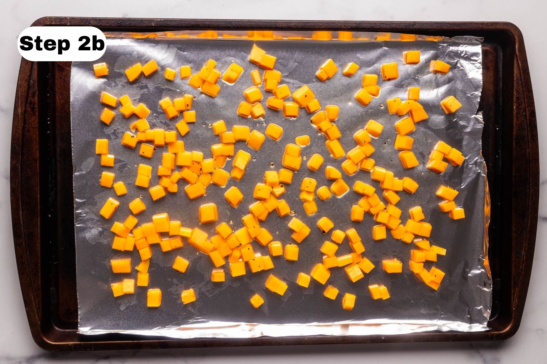 Diced butternut squash on a baking sheet lined with foil