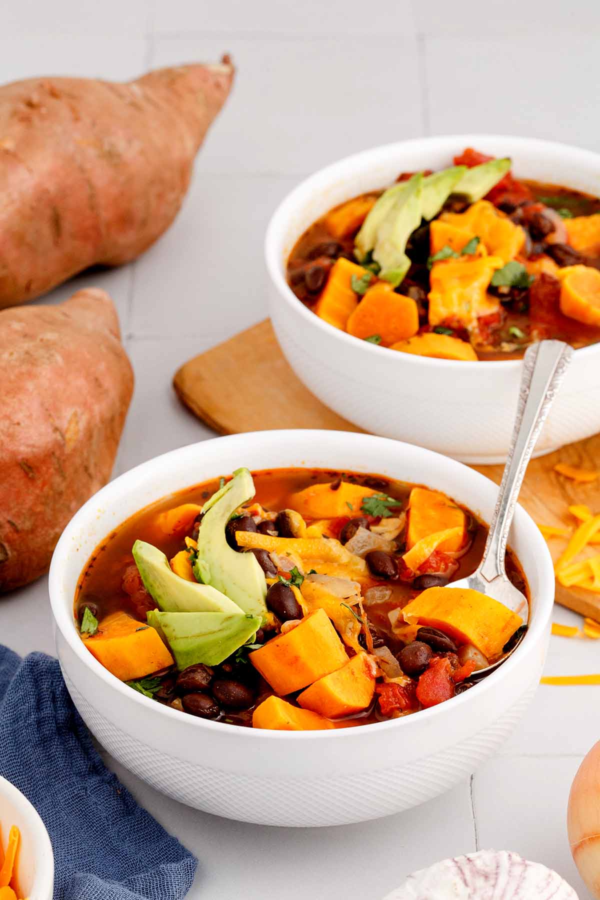 Close up of a serving of sweet potato black bean soup in a white bowl with a spoon