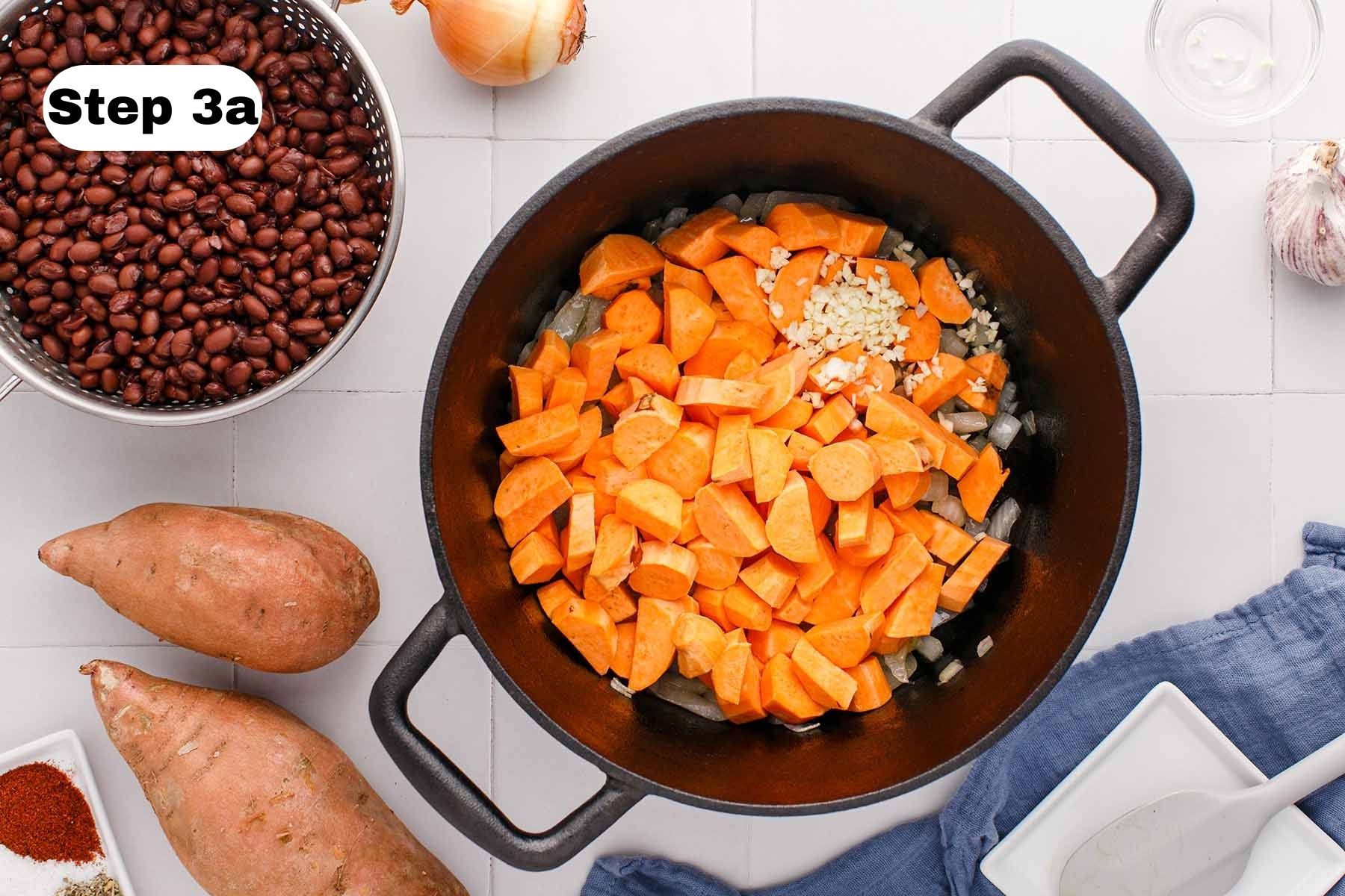 Uncooked chopped sweet potato and minced garlic in a soup pot