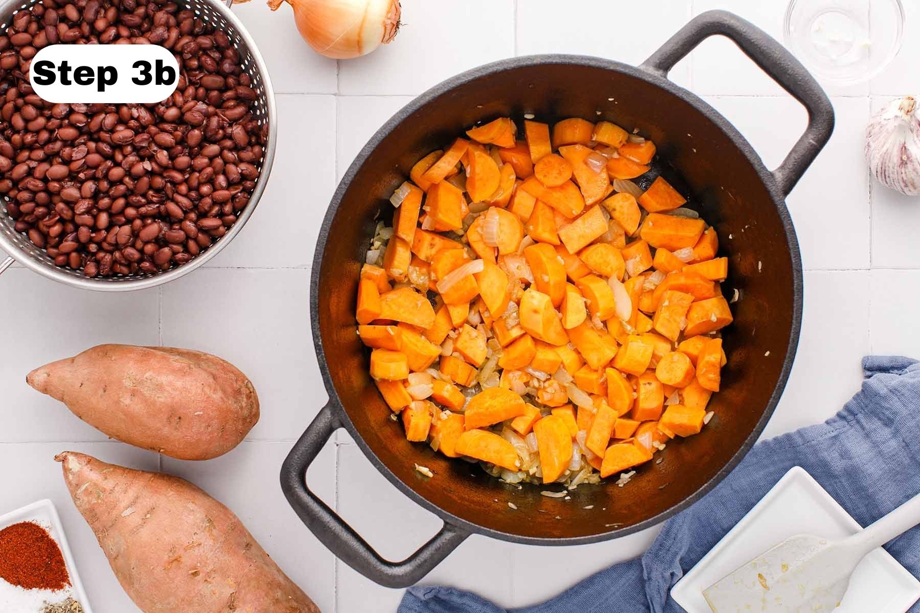 Sauteed chopped sweet potato, garlic, and onion in a soup pot