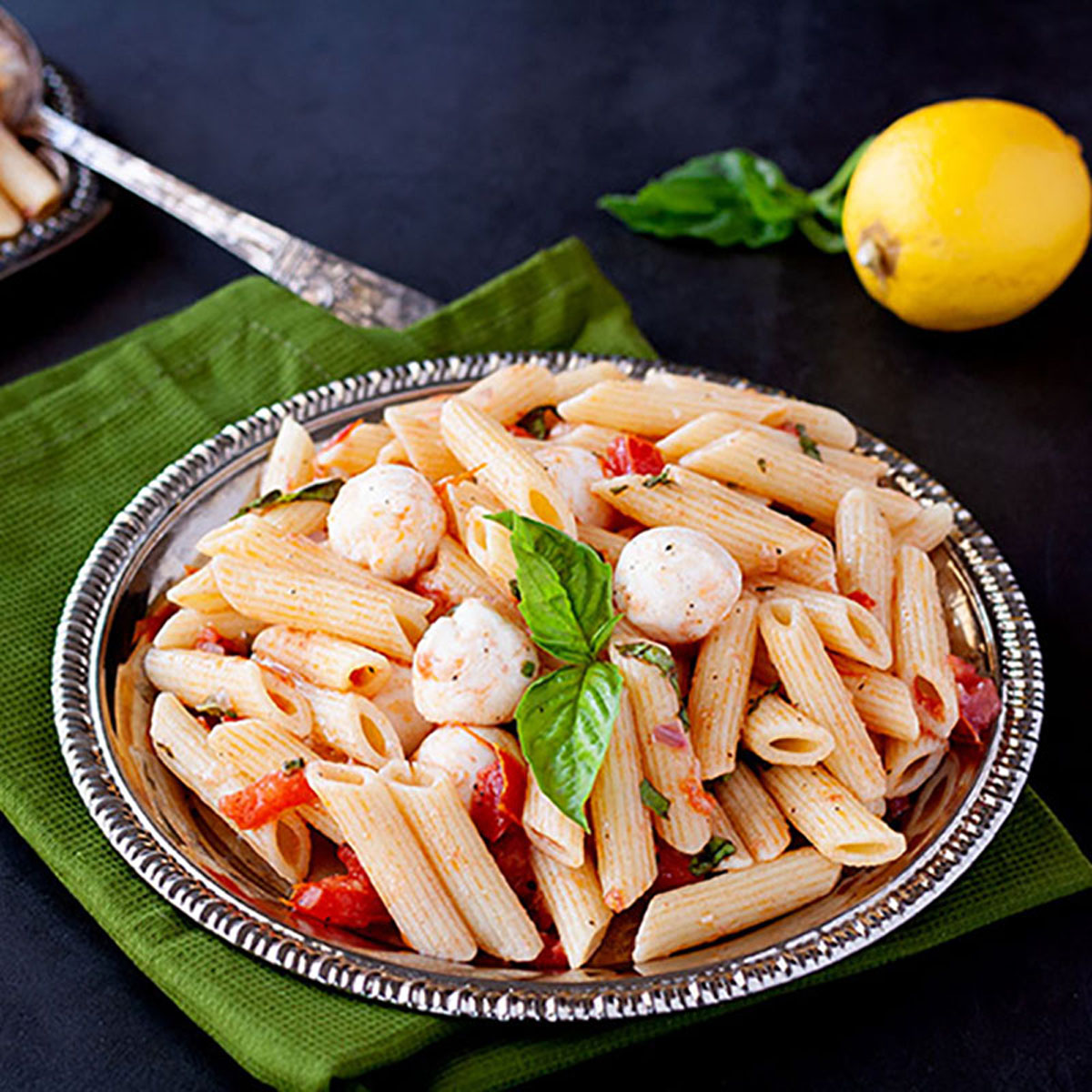 Serving of caprese pasta on a silver plate.