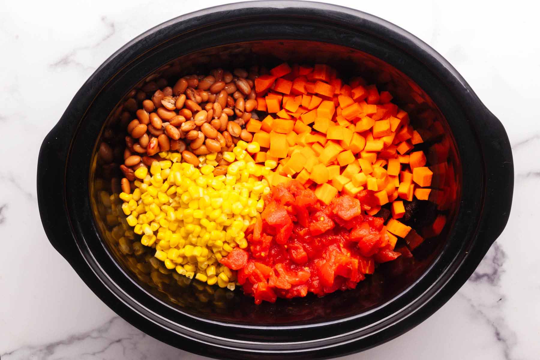 Pinto beans, chopped carrots, corn, and diced tomatoes in a slow cooker with stew meat and onion