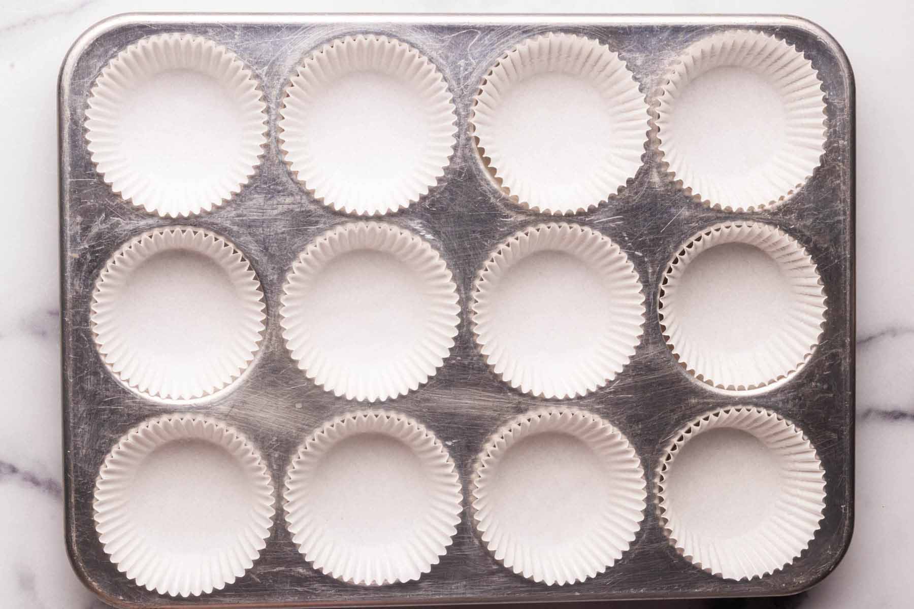 Paper cupcake liners in each well of a 12-cup standard muffin tin