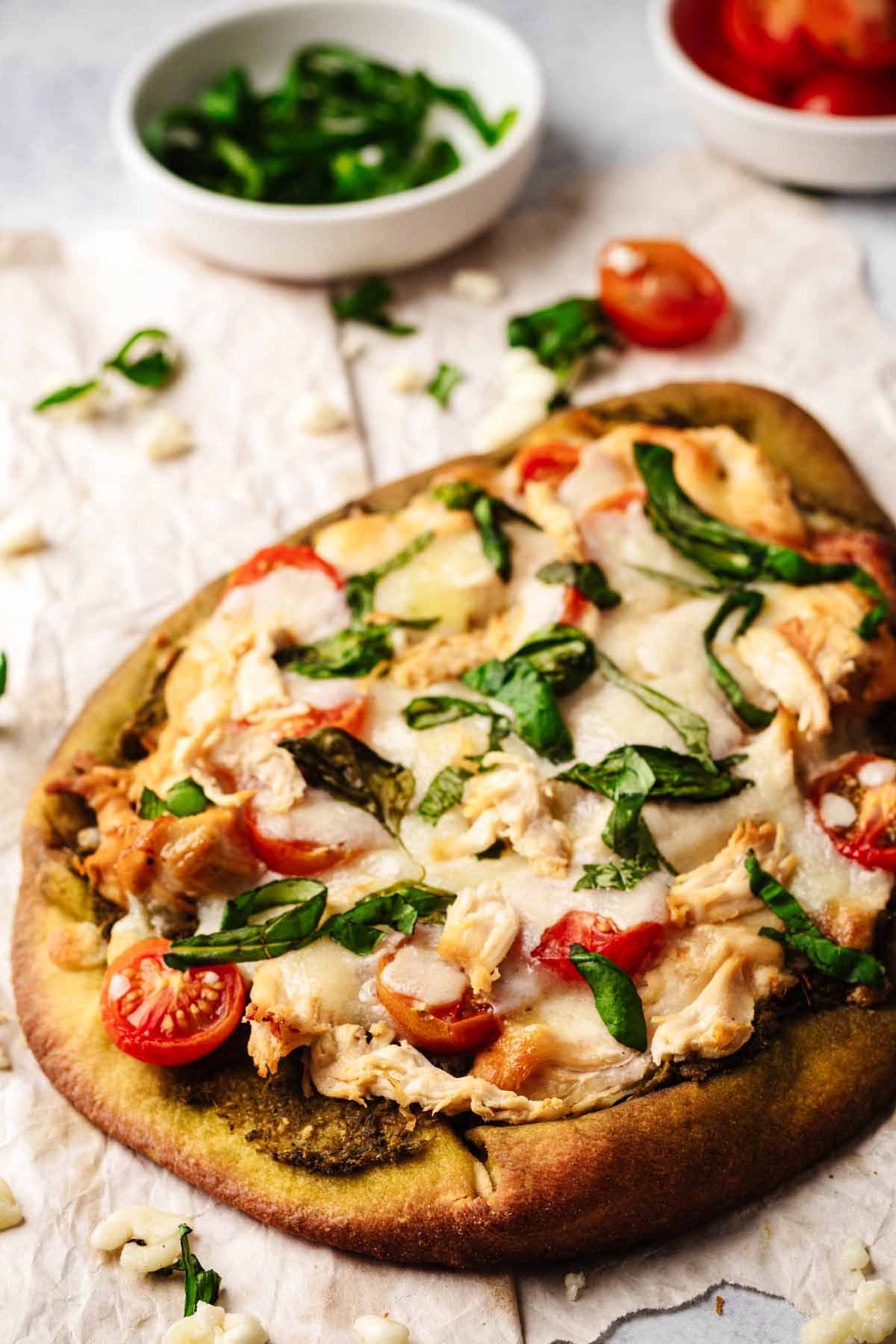 Close up of a whole chicken pesto flatbread on crumpled paper