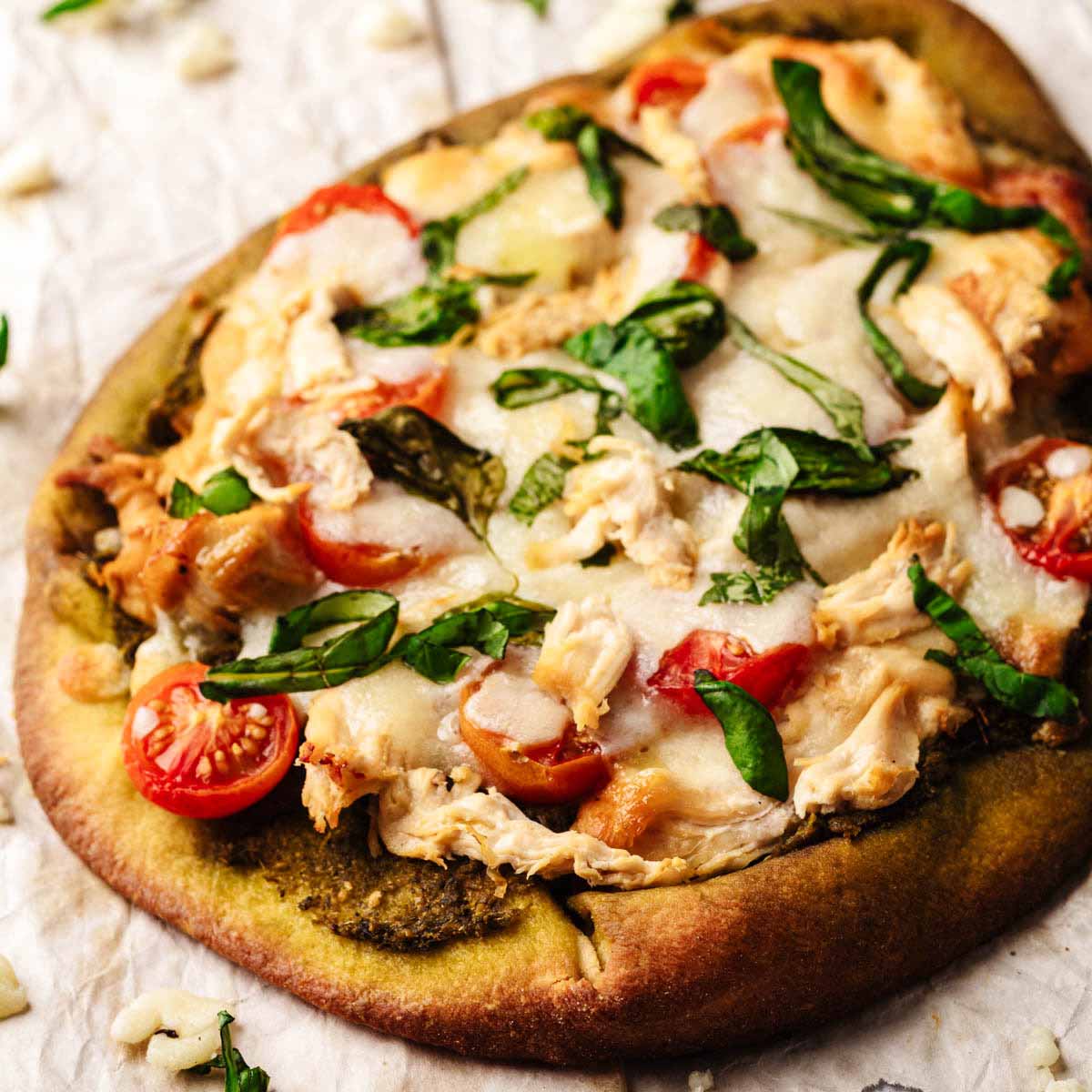 Close up of a whole chicken pesto flatbread on crumpled paper