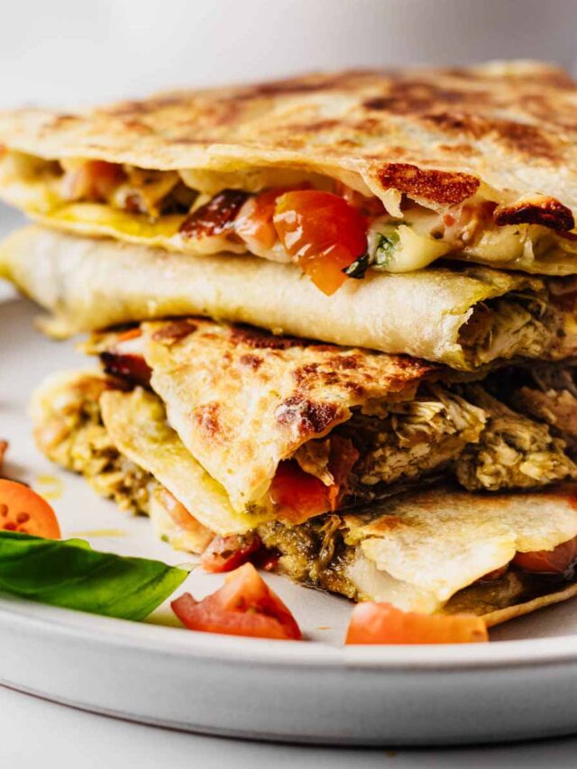 Chicken pesto quesadillas cut into triangles and stacked on a light grey plate