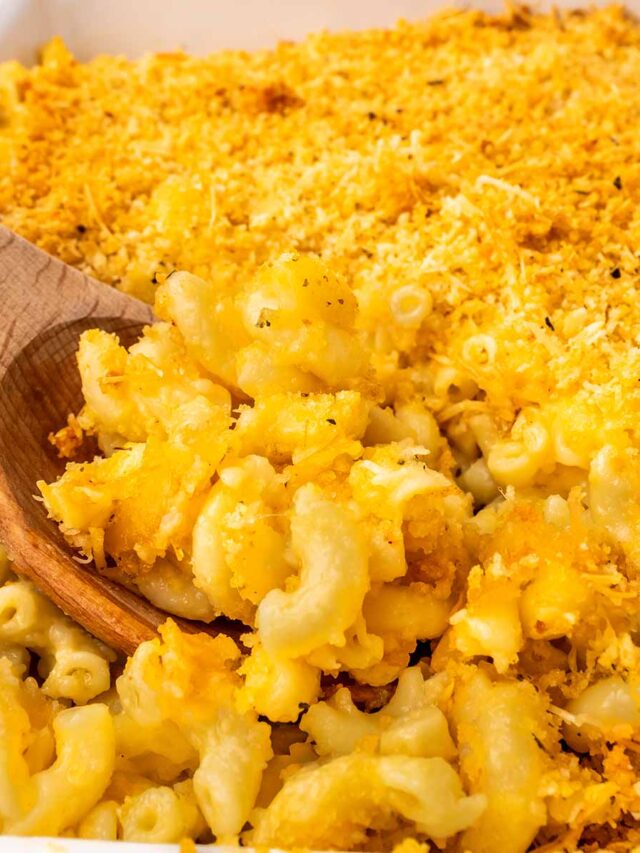 Close-up of creamy baked macaroni and cheese topped with a golden, crispy breadcrumb crust, with a wooden spoon scooping out a portion.