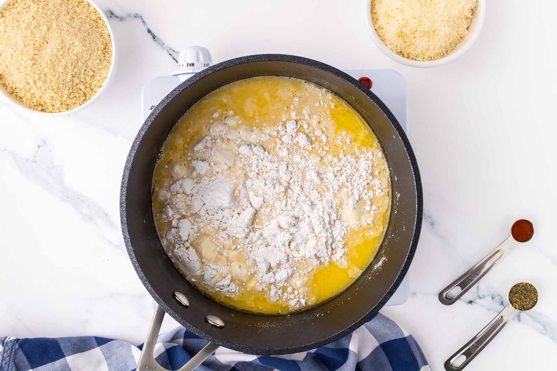 Flour added to melted butter in a saucepan, beginning the roux for the cheese sauce in a baked macaroni and cheese recipe.