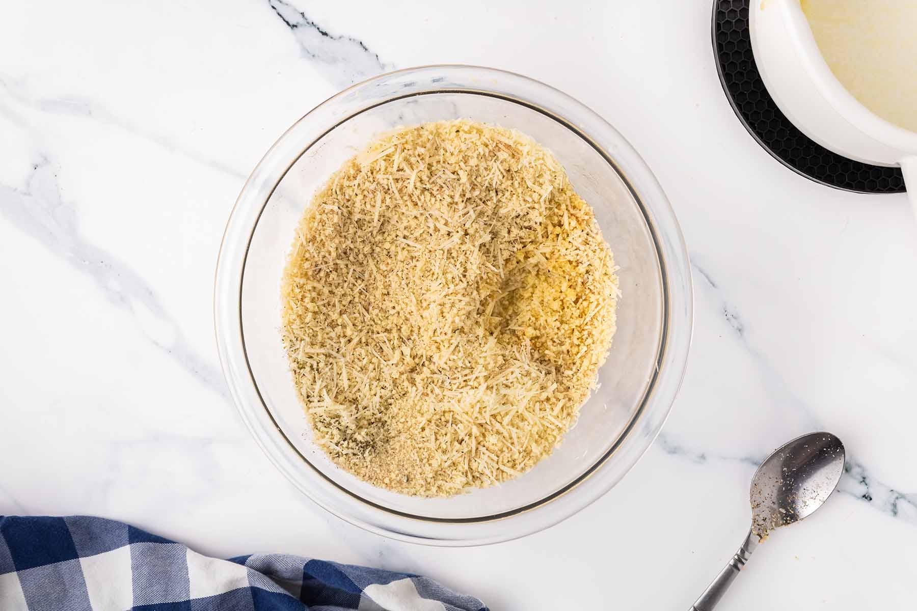 A glass bowl with mixed breadcrumbs, grated parmesan, and seasonings, ready to be used as a topping for baked macaroni and cheese.