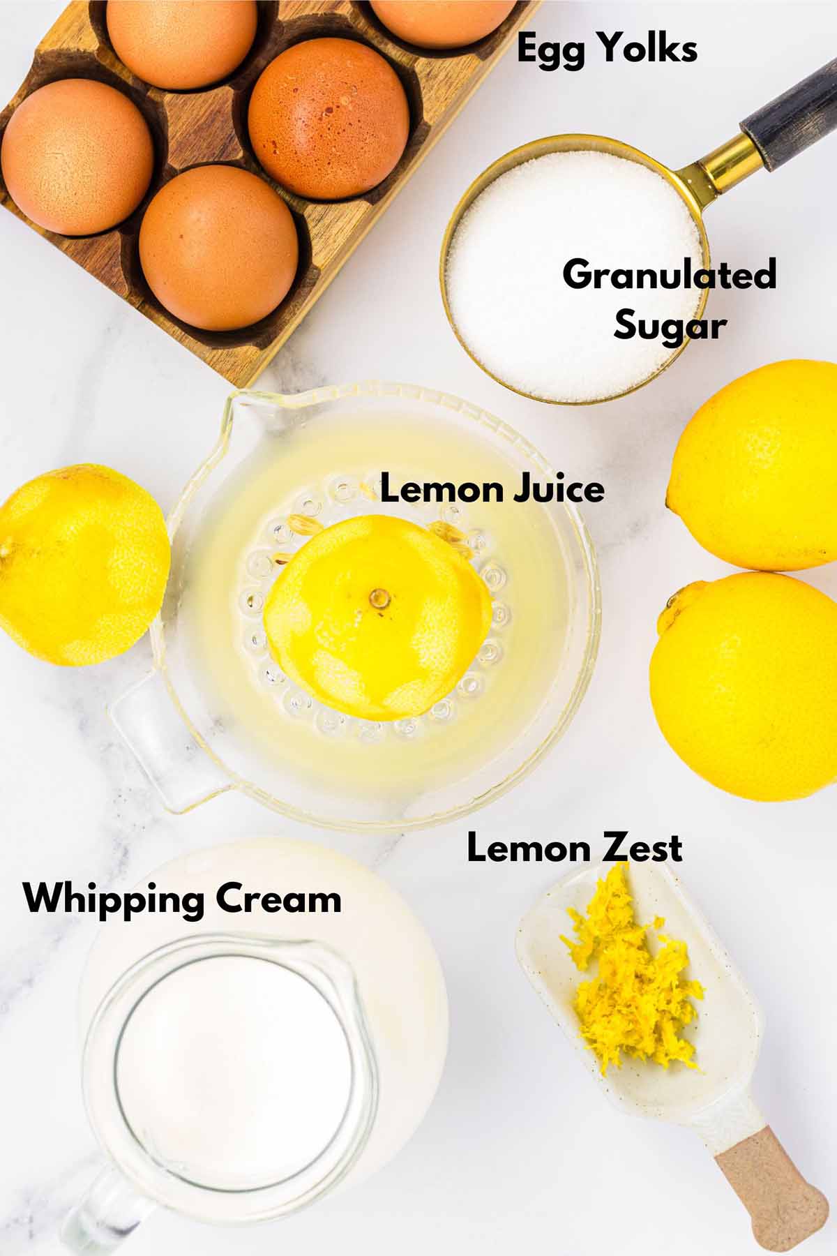 Top-down view of ingredients for lemon mousse: egg yolks, granulated sugar, lemon juice, lemon zest, and whipping cream.