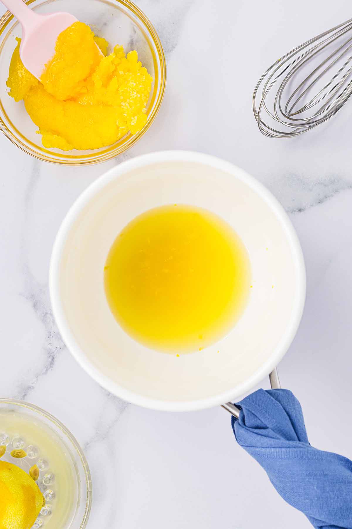 Bowl of lemon juice and zest over a pot, with a separate bowl of egg yolk and sugar mixture beside it. Step 2 of making lemon curd for lemon mousse.