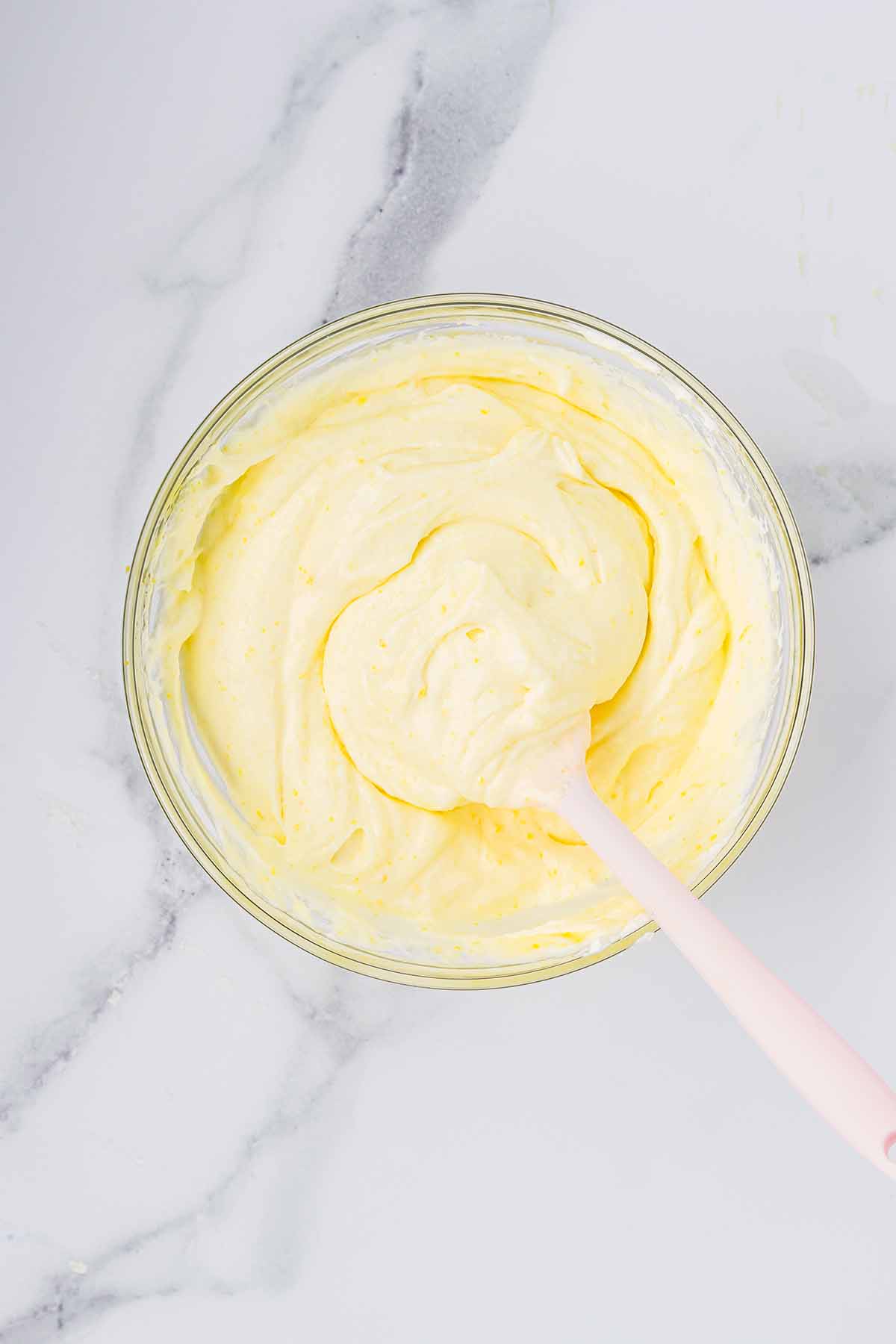 Smooth lemon mousse in a bowl with a spatula. Step 8 of making lemon mousse.