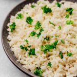 Fluffy Garlic Parmesan Rice served in a dark bowl, topped with fresh parsley for a pop of color and flavor.