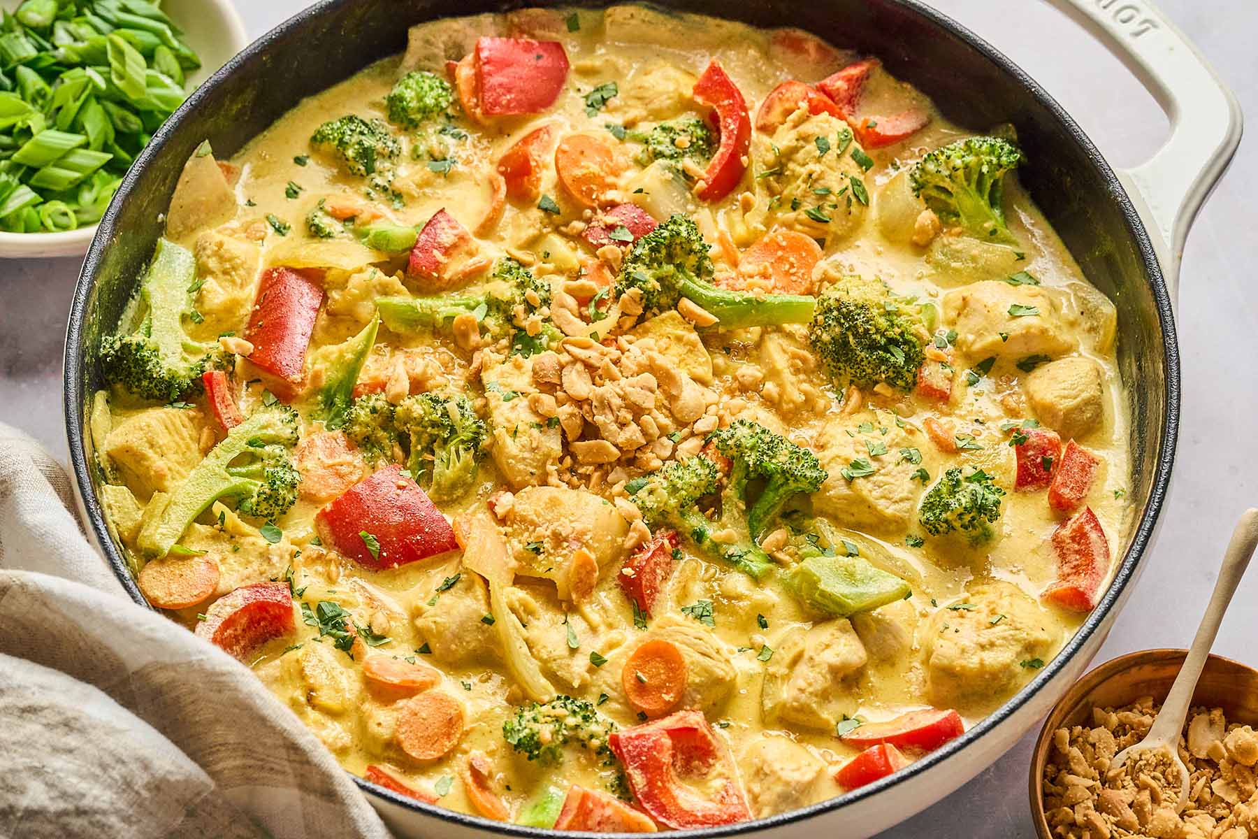 Yellow curry chicken with vegetables in a white skillet