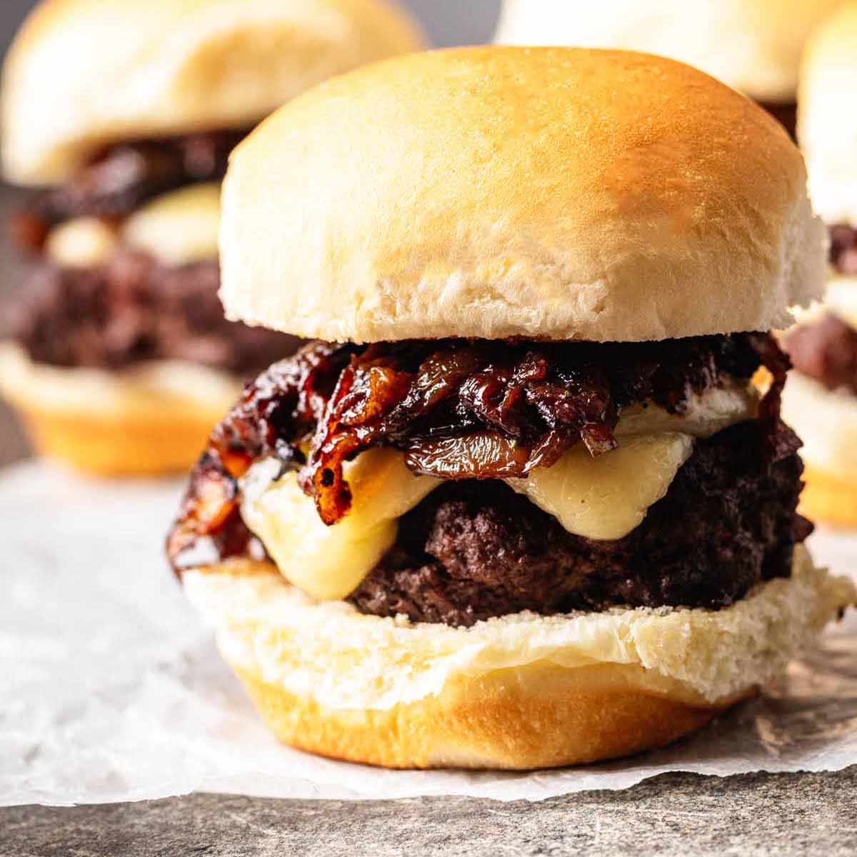 Close-up of a French onion slider with melted cheese and caramelized onions on a soft bun.