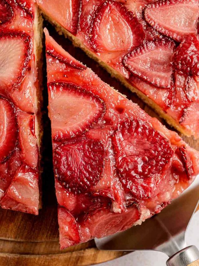 Close-up of strawberry upside down cake with a slice being lifted, showing caramelized baked strawberries on top of a golden, tender cake layer