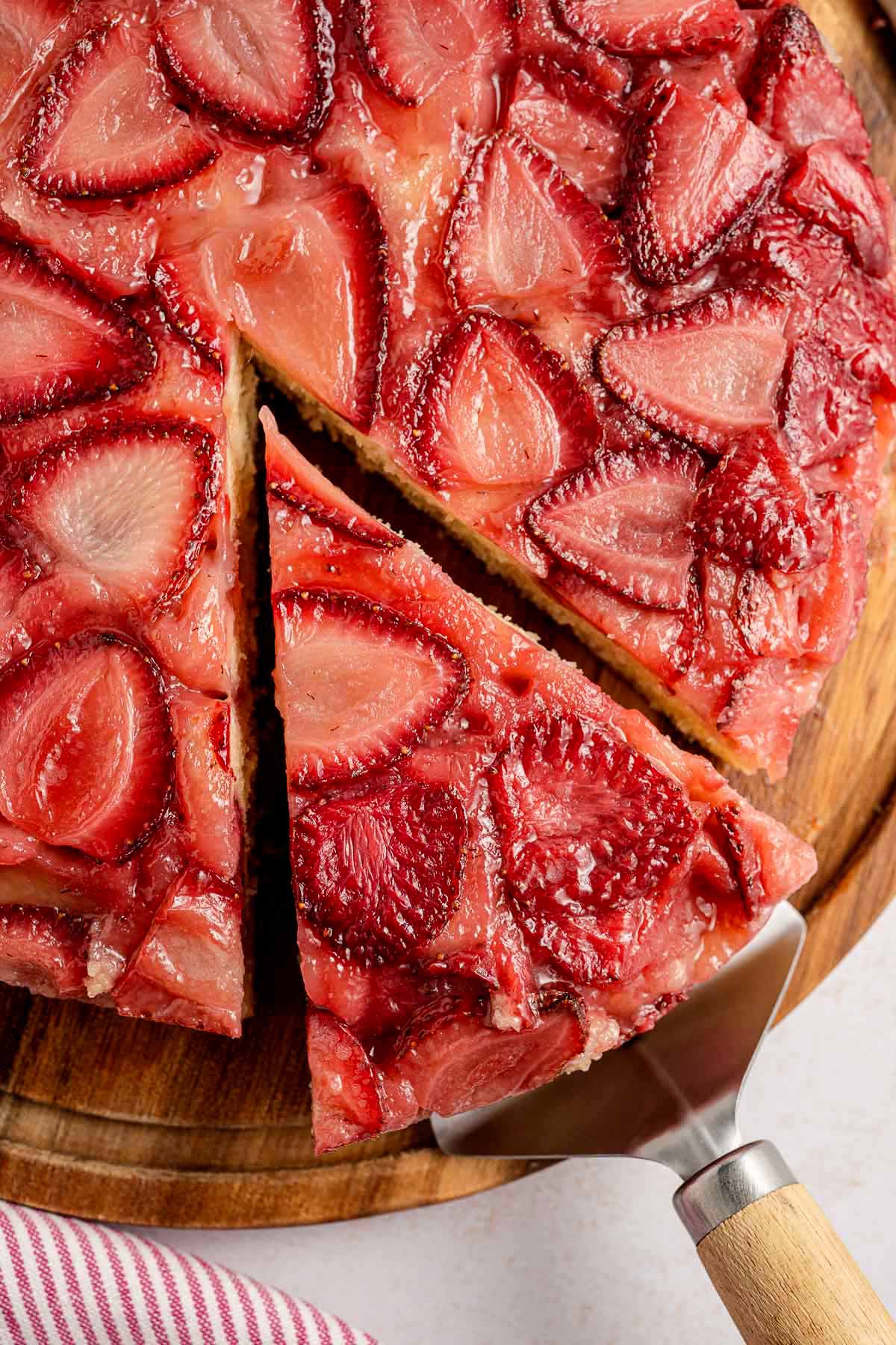 Close-up of strawberry upside down cake with a slice being lifted, showing caramelized berries and a golden cake base