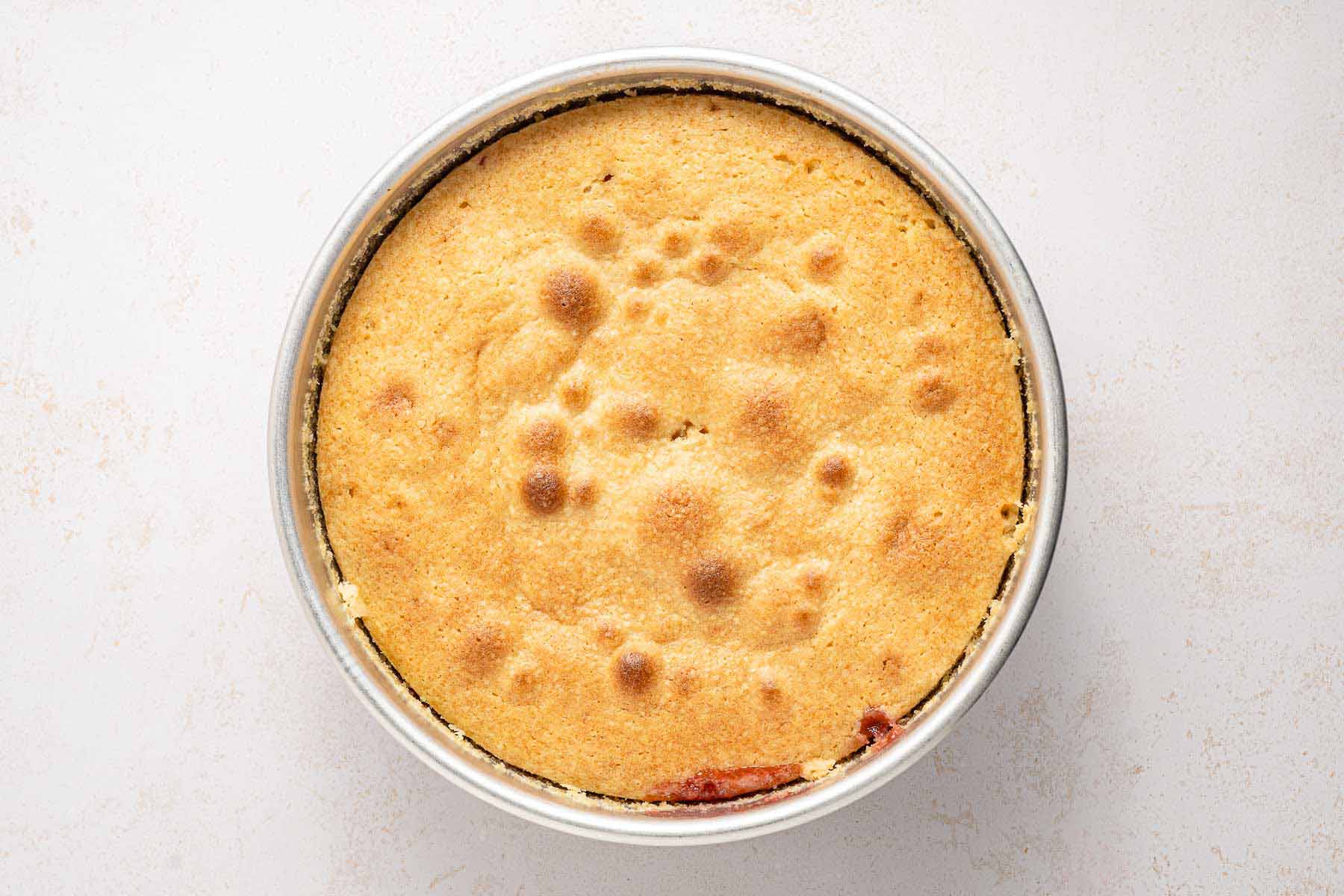 Golden brown strawberry upside down cake freshly baked in a round pan, ready to cool before inverting