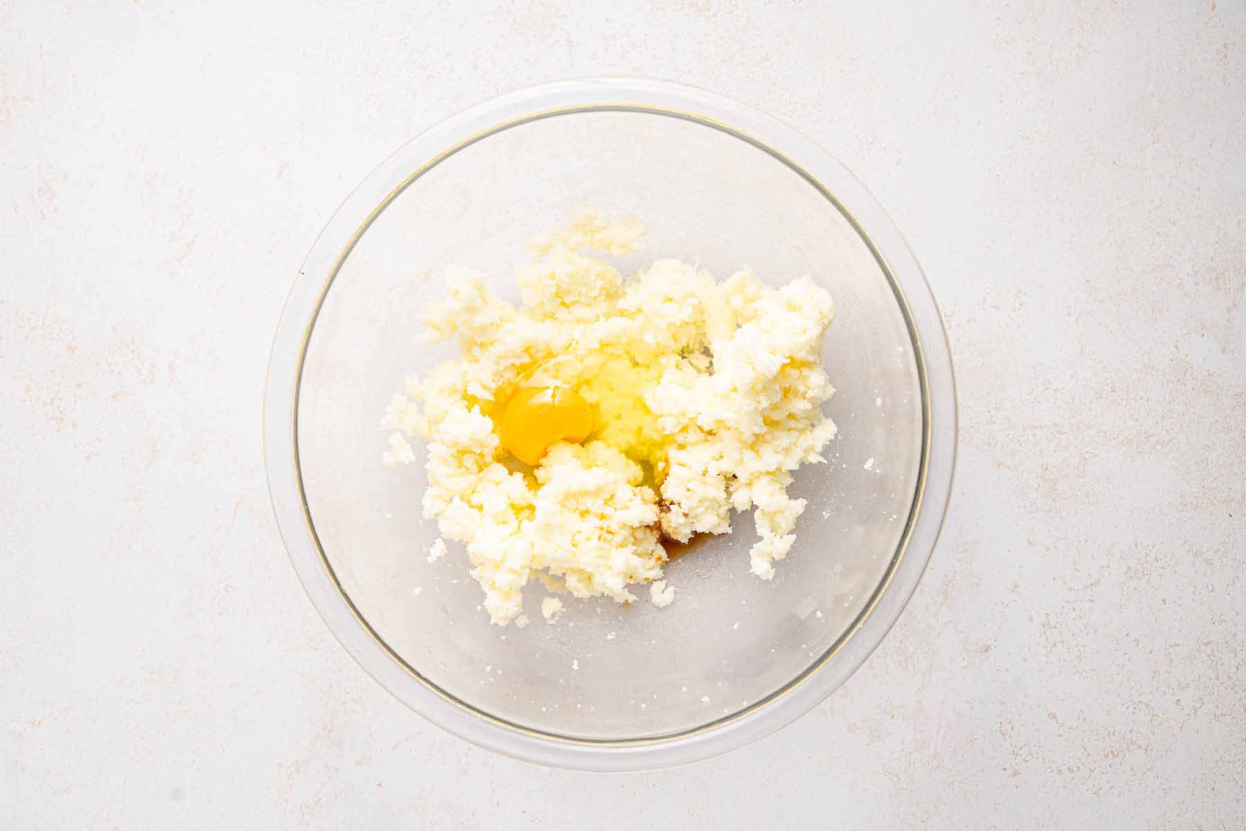 Egg added to creamed butter and sugar in a glass bowl for the cake batter