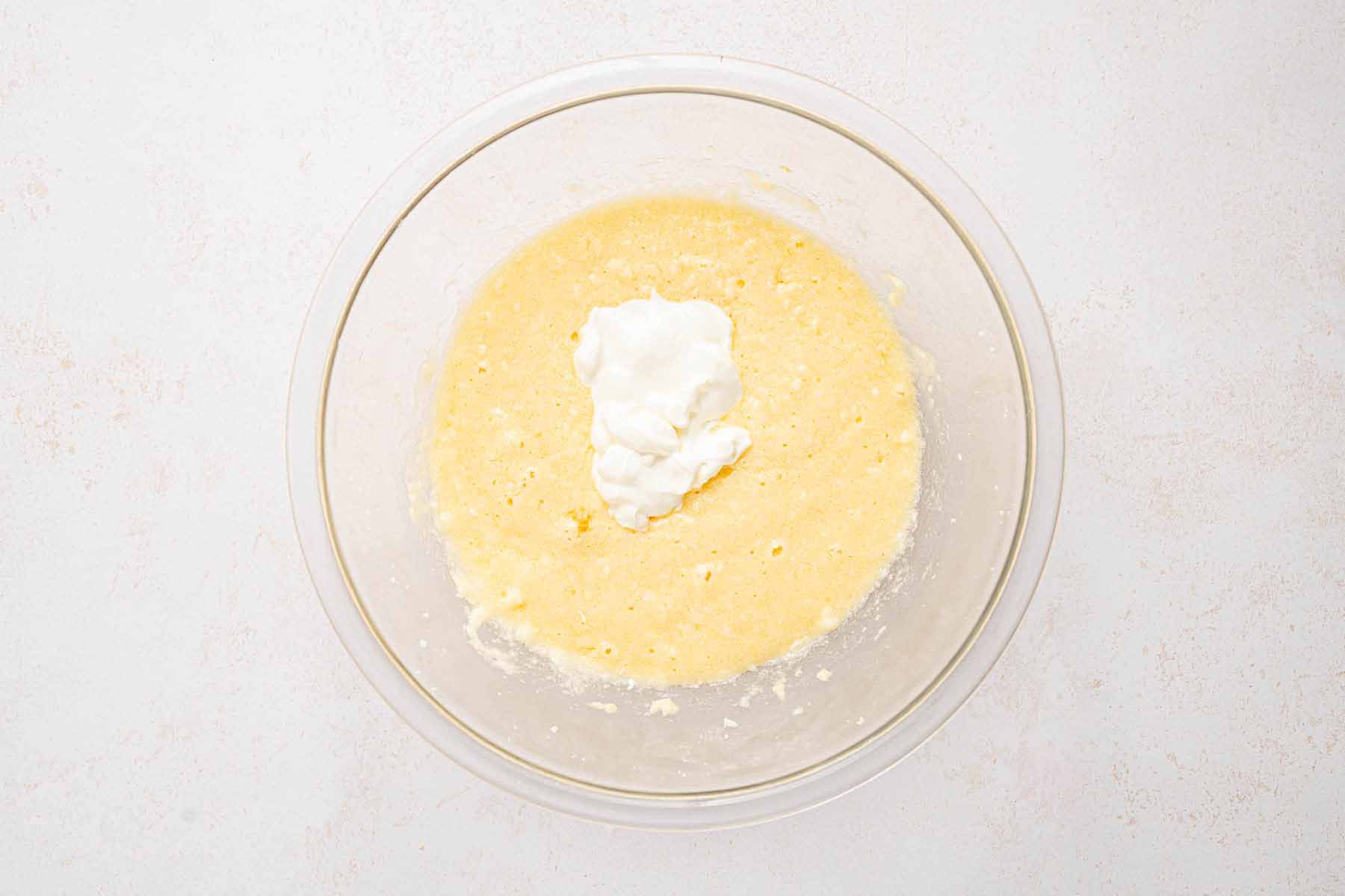 Sour cream added to the creamed butter, sugar, and eggs in a glass bowl for the cake batter