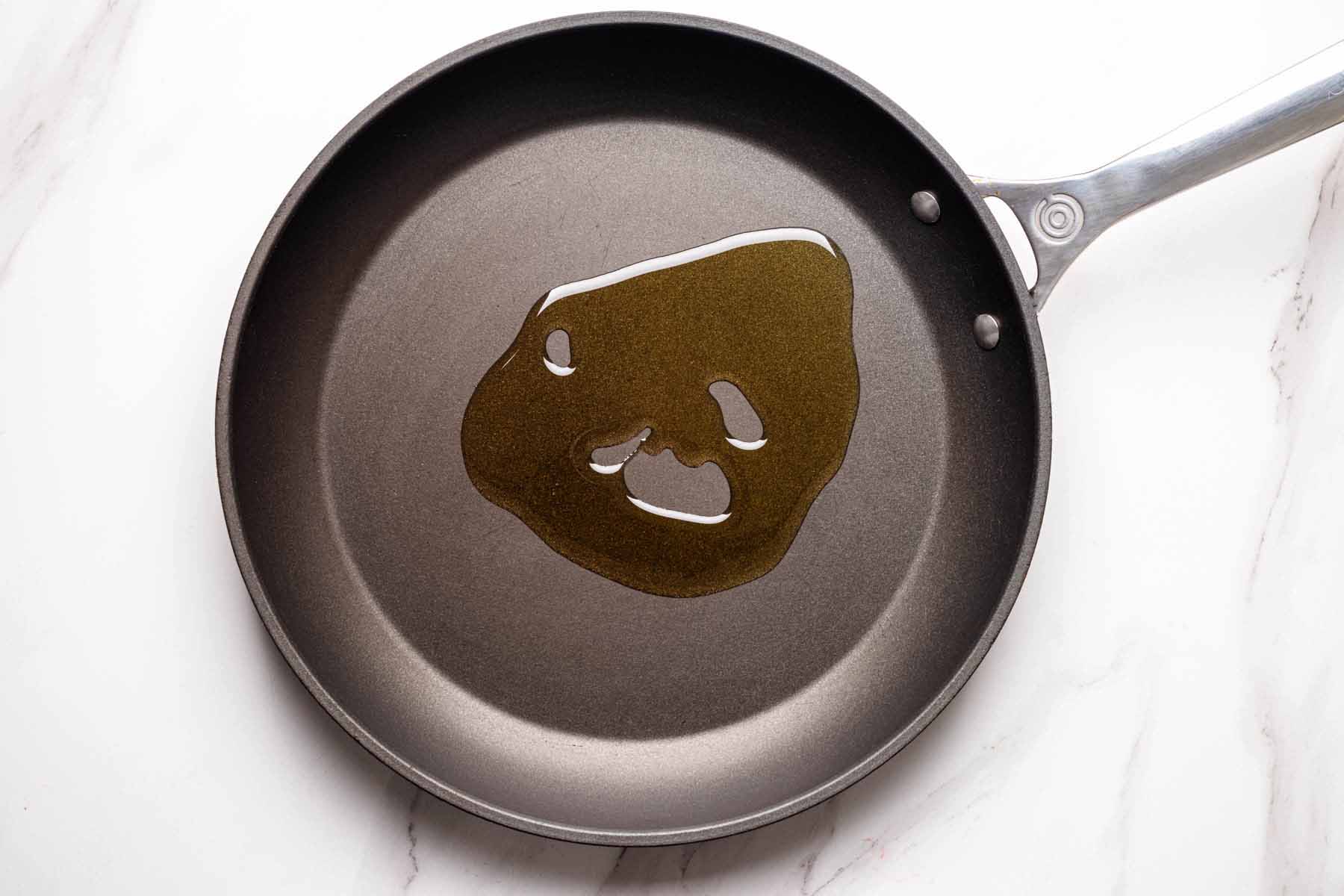Overhead view of a large skillet with olive oil heating in the center, ready for cooking shrimp.