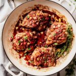Finished strawberry chicken in a white skillet, topped with strawberry balsamic glaze, toasted almonds, and fresh herbs.