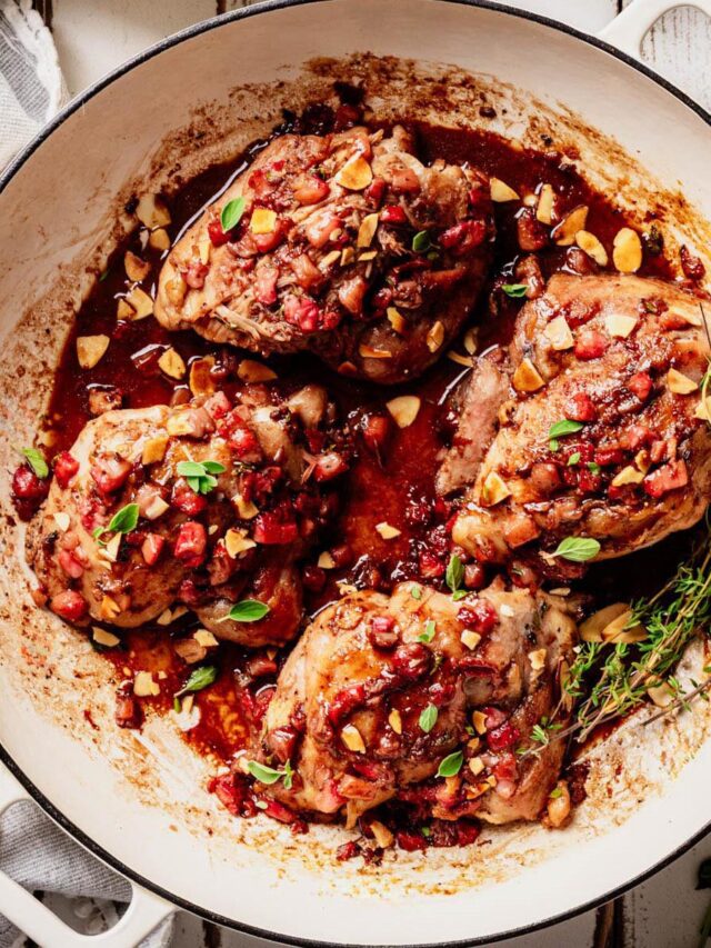 Finished strawberry chicken in a white skillet, topped with strawberry balsamic glaze, toasted almonds, and fresh herbs.