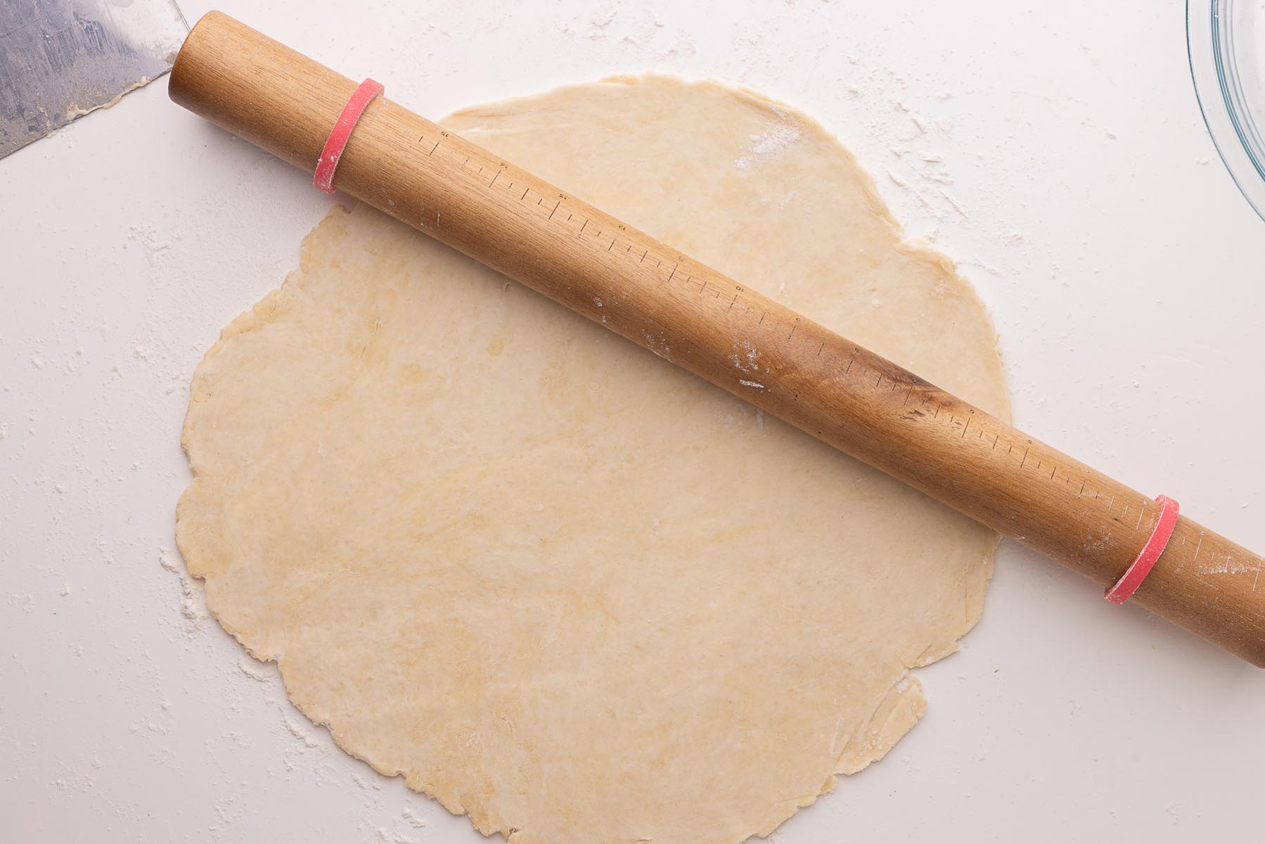 Rolled-out pie dough on a floured surface with a rolling pin resting across it, showing even thickness and flakiness.