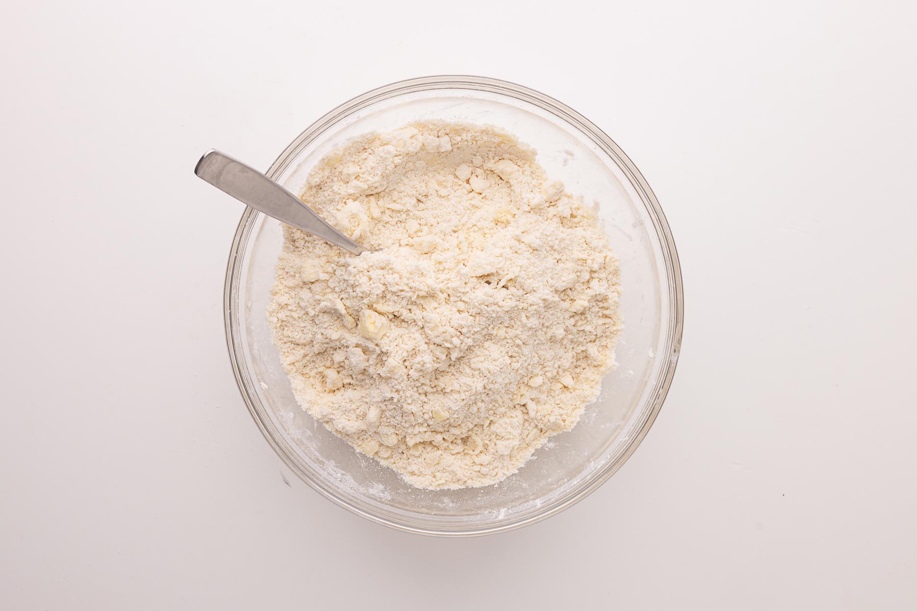Flour and butter mixture after pressing and flaking, showing visible butter shards in the bowl with a fork.