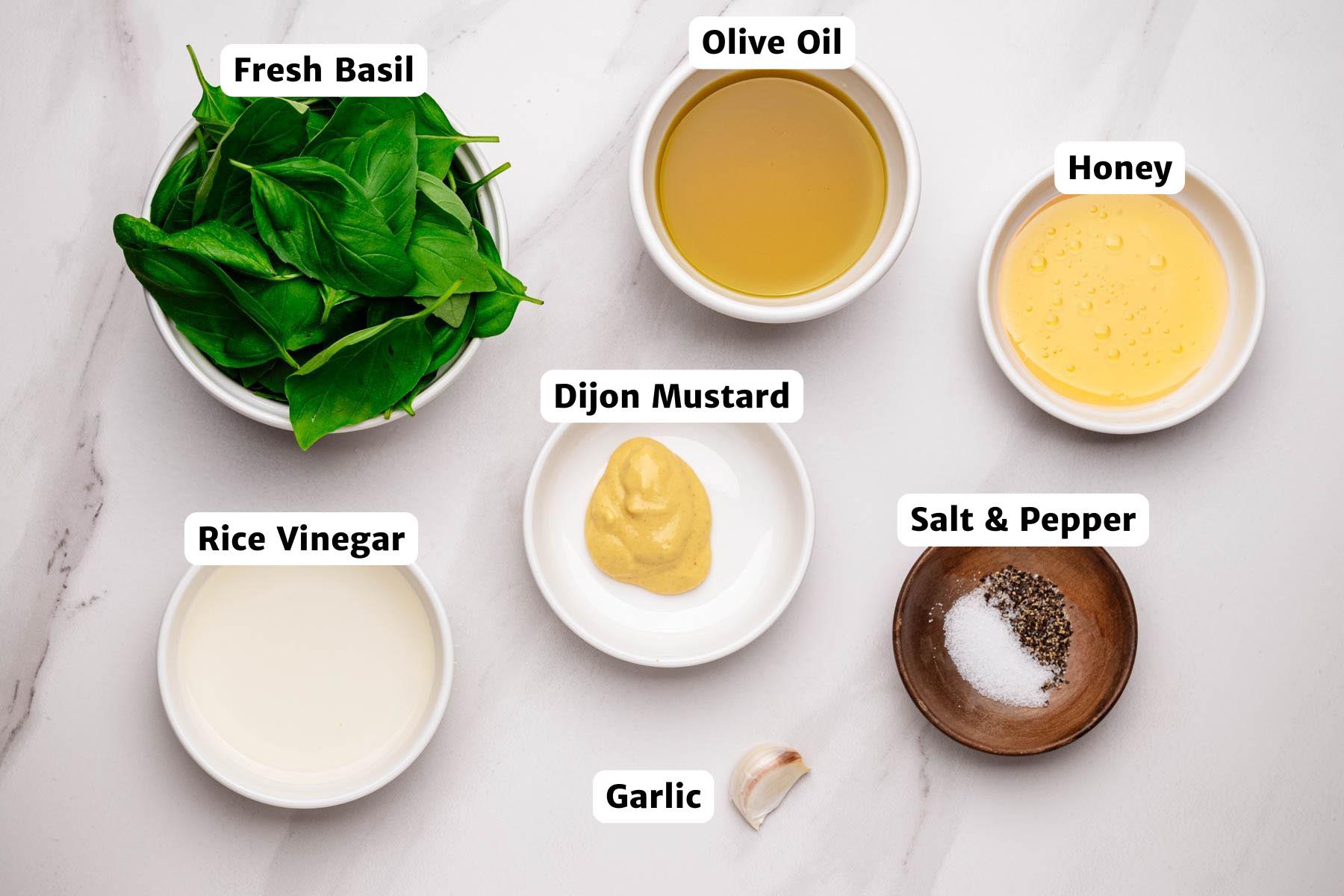 Labeled ingredients for basil vinaigrette on a white surface.