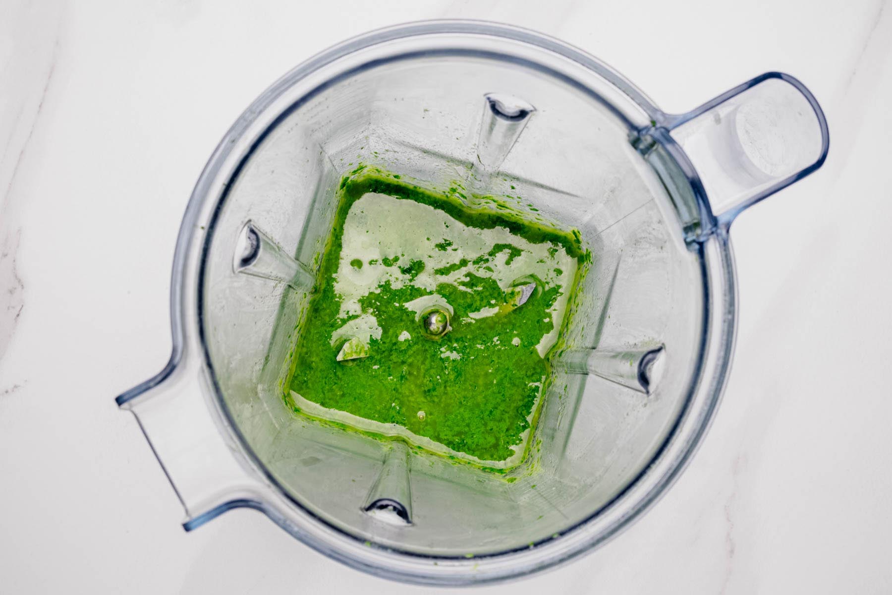 Blended basil vinaigrette in a blender with a smooth, vibrant green consistency.