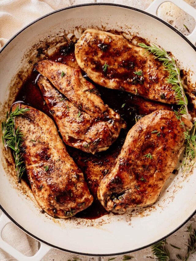 Golden-brown chicken cutlets in a glossy bourbon-maple glaze, garnished with fresh thyme and rosemary, in a white enameled skillet.