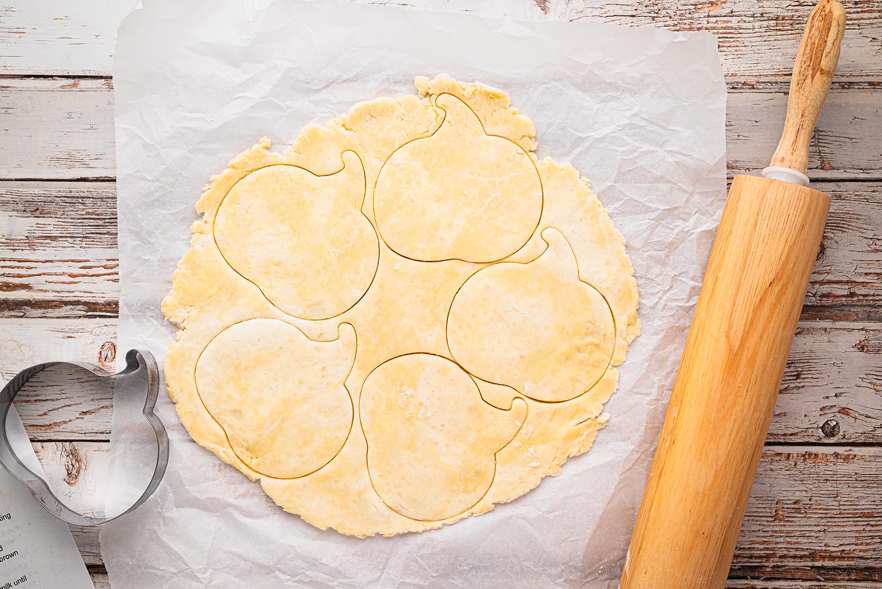 Pie crust rolled out on a floured surface and cut into pumpkin shapes with a cookie cutter.