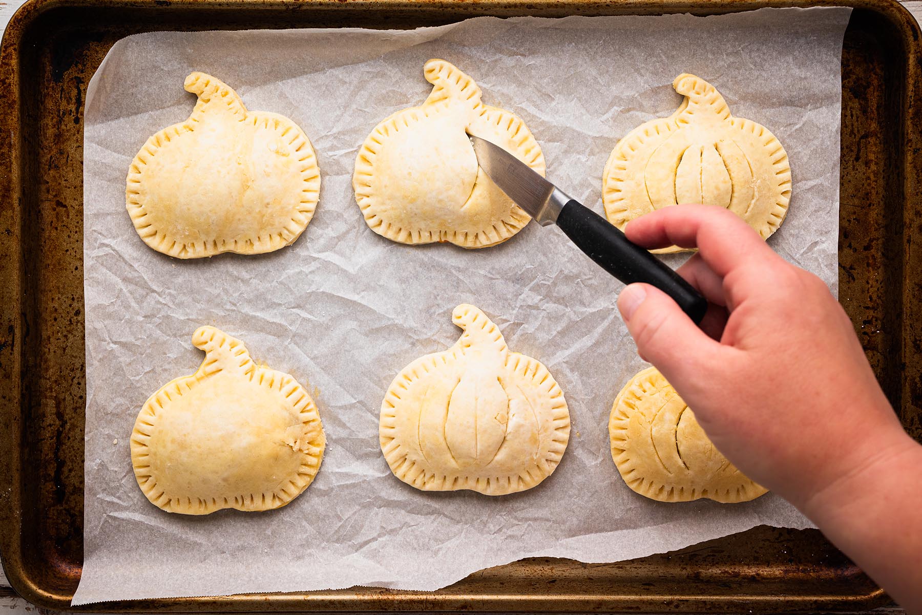 Unbaked pumpkin hand pies with small steam vents cut into the top crust.