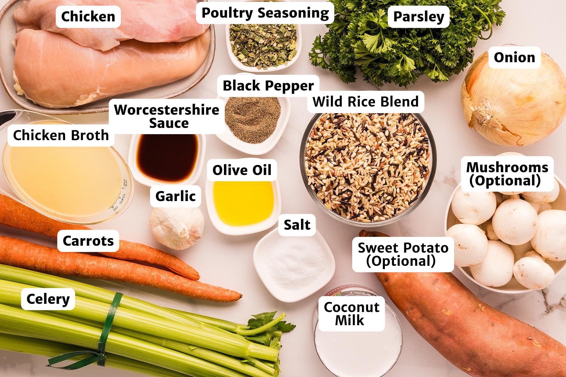 Overhead image of labeled ingredients for chicken and wild rice soup: raw chicken breasts, wild rice blend, coconut milk, chicken broth, olive oil, Worcestershire sauce, garlic, onion, celery, carrots, parsley, poultry seasoning, salt, black pepper, plus optional sweet potato and mushrooms.