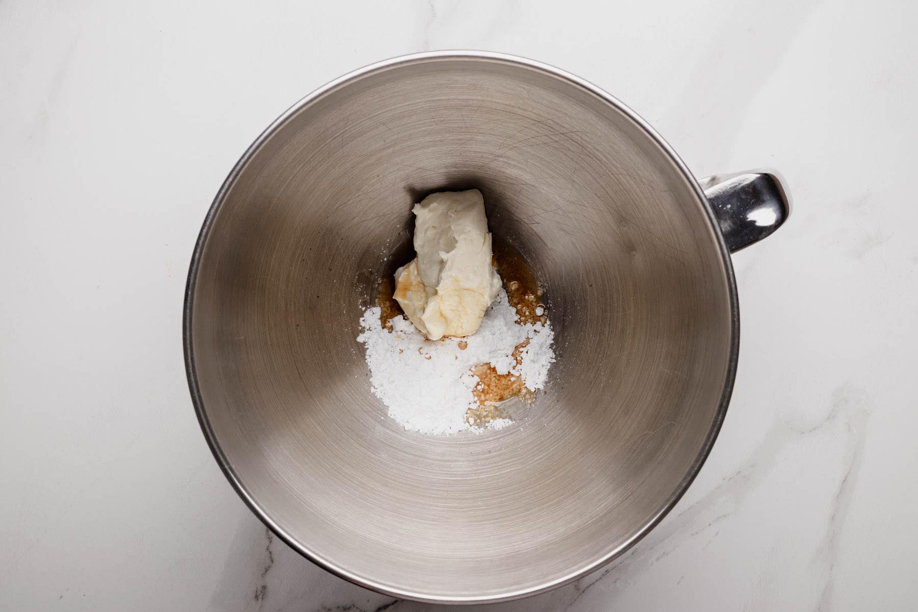Mixing bowl with cream cheese, powdered sugar, and vanilla before mixing for whipped cream topping.