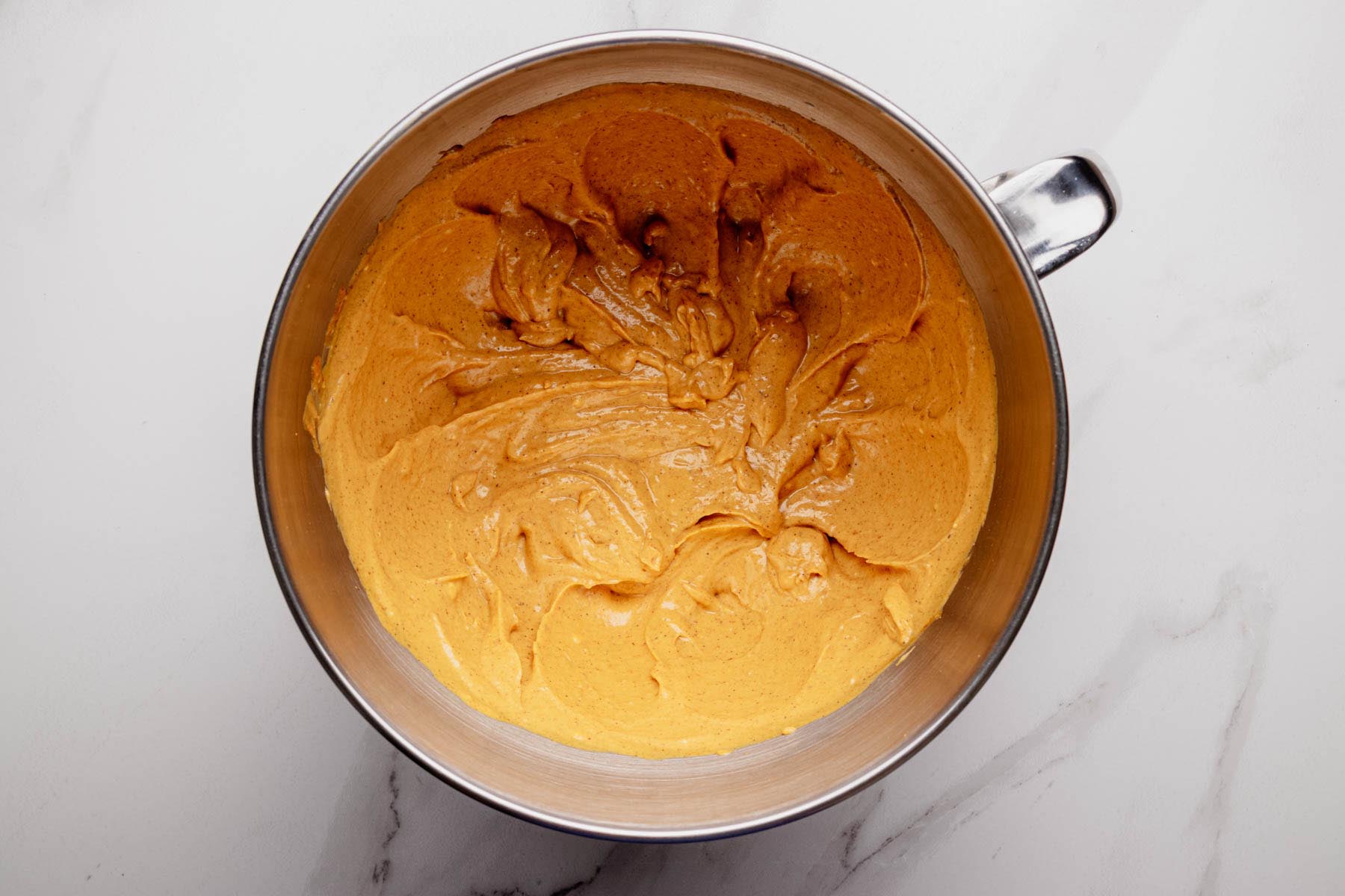 Pumpkin cheesecake filling mixed until smooth in a stainless steel bowl.