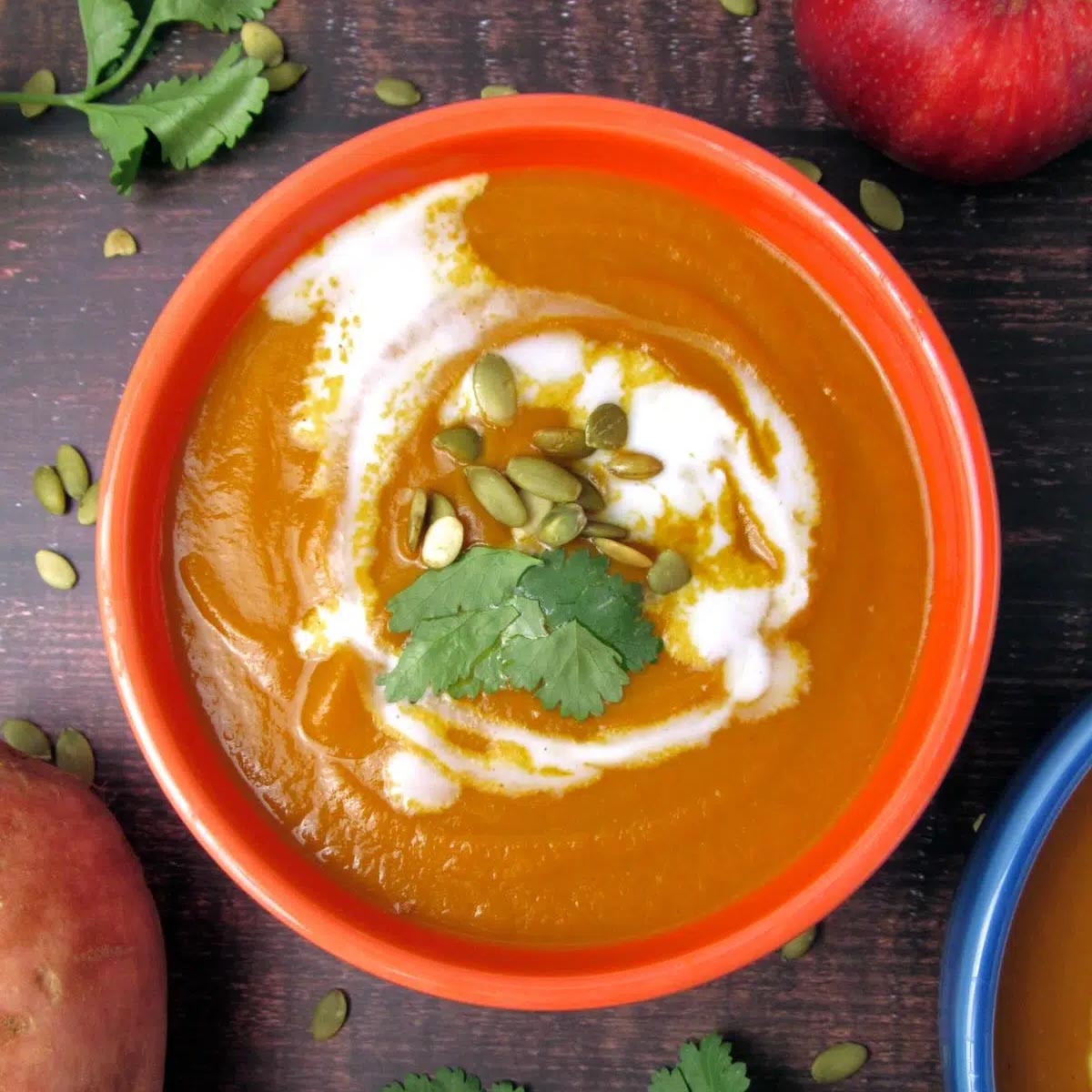 Creamy pumpkin curry soup topped with coconut swirl, pepitas, and cilantro.