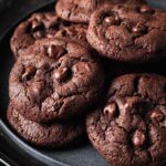 Close-up of double-chocolate peanut butter cookies arranged on a dark plate, highlighting their soft texture and glossy chocolate chips.